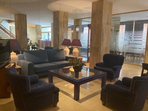 a living room with couches and a table and chairs at Hotel Condal in Salamanca