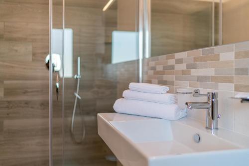 a bathroom with a sink and a shower with towels at Hotel Centrale in Lignano Sabbiadoro