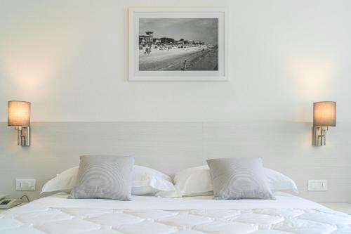 a bedroom with a white bed with a picture on the wall at Hotel Centrale in Lignano Sabbiadoro
