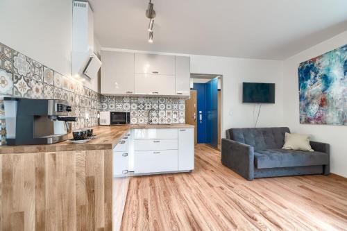 a kitchen with white cabinets and a couch in a room at Apartament 400 Apartamenty No 1 Stare Miasto in Szczecin