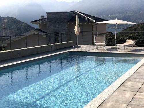 einen Pool mit 2 Stühlen und einem Sonnenschirm in der Unterkunft Casa Roxy in Colico