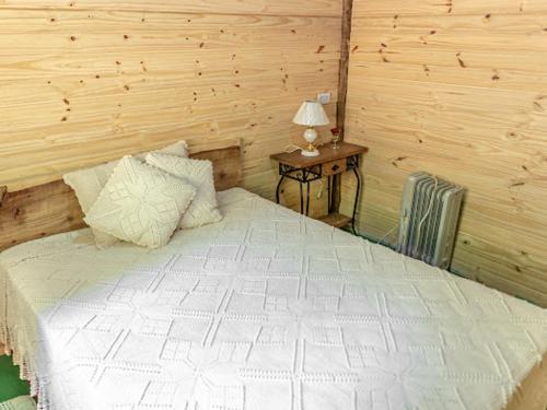 um quarto com uma cama e uma mesa com um candeeiro em Sítio flor da montanha em São Bento do Sapucaí