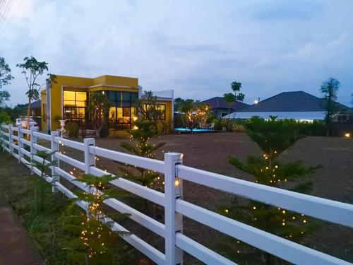 une clôture blanche devant une maison éclairée dans l'établissement Colorful Pool Villa, Chiang Rai, Thailand, à Chiang Rai