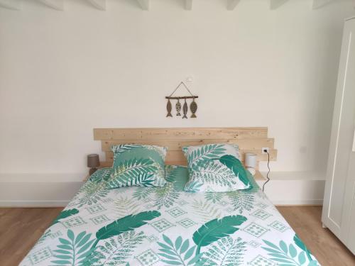 a bed with green and white sheets and pillows at Joli T3 près du phare in Calais