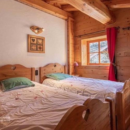 a bedroom with two beds in a log cabin at La Centaurée in Bonneval-sur-Arc