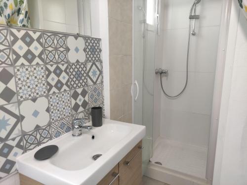 a bathroom with a white sink and a shower at Joli T3 près du phare in Calais