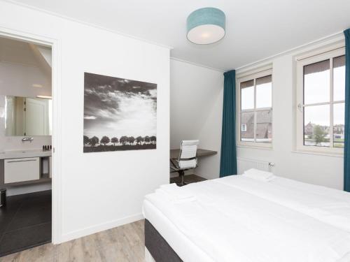1 dormitorio con cama blanca, escritorio y lavamanos en Beautiful, thatched villa with a sauna at the Tjeukemeer, en Delfstrahuizen