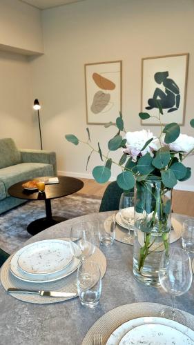 a table with plates and a vase of flowers on it at Park Premium Apartments in Birštonas