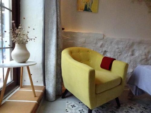 a yellow chair in a room with a vase at La Solana, alojamiento y alfarería in Arenas de San Pedro