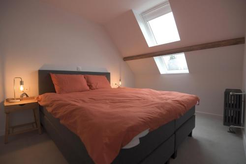 a bedroom with a bed with orange sheets and a table at Gastenkamers huYze K in Zottegem