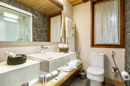 a bathroom with a sink and a toilet and a mirror at Hotel Toriba in Campos do Jordão