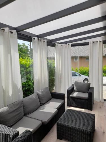 a living room with a couch and chairs and windows at MELÁNIA in Vonyarcvashegy