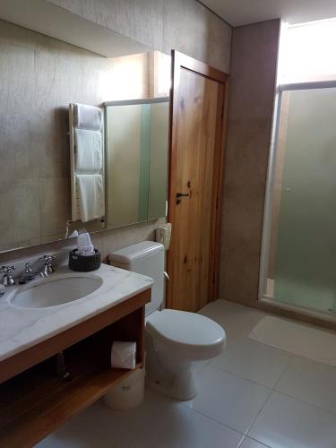 a bathroom with a toilet and a sink and a mirror at Hotel Toriba in Campos do Jordão