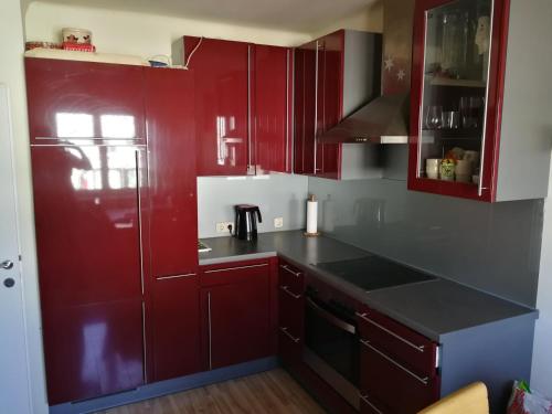 a kitchen with red cabinets and a black counter top at Doppelhaushälfte mit Garten in Linz