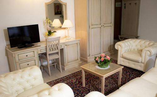 sala de estar con muebles blancos y TV en Toscana Wellness Resort, en Arcidosso