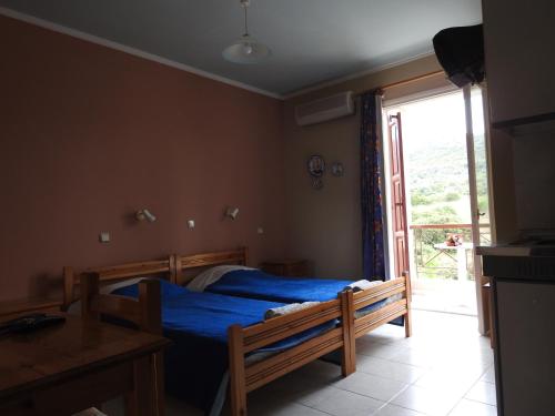 a bedroom with a bed with blue sheets and a window at ChiosRoomsMaria in Armólia