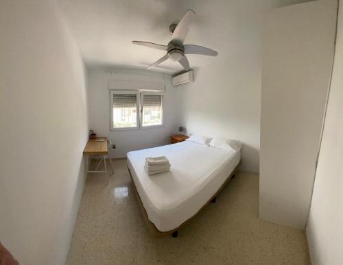 a white bedroom with a bed with a ceiling fan at Oasis Urbano Ciudad Expo in Mairena del Aljarafe