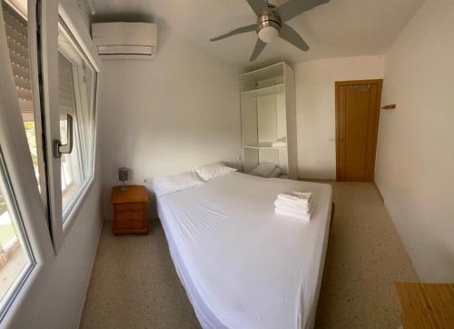 a bedroom with a white bed with a ceiling fan at Oasis Urbano Ciudad Expo in Mairena del Aljarafe
