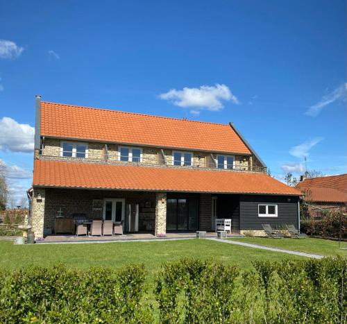 een groot bakstenen huis met een oranje dak bij B&B Aasterbergerhoeve in Echt