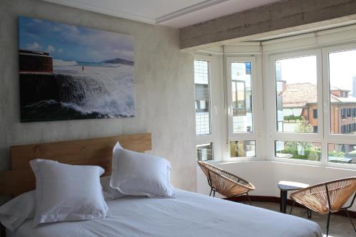 a bedroom with a bed and a large window at Apartamentos Zarautz Playa, con piscina y garaje in Zarautz