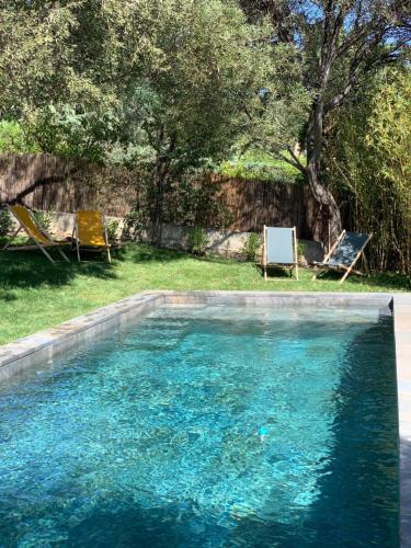 a swimming pool with two lounge chairs in a yard at Le Rossignol 1, Aiguebelle plage in Le Lavandou