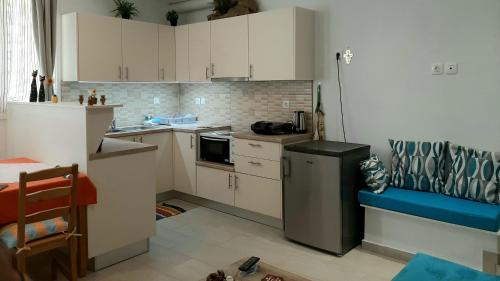una pequeña cocina con armarios blancos y nevera. en Quiet, colourful home in Cyclades, en Konizopí