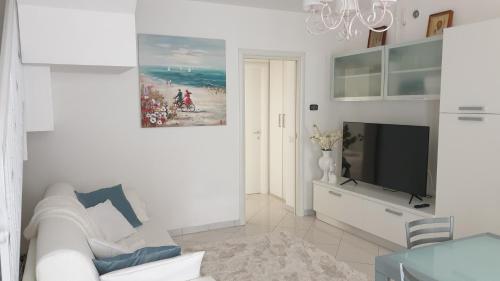a white living room with a white couch and a tv at B&B El Dorado in Lido di Pomposa