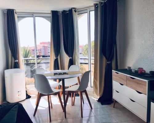 een kamer met een tafel en stoelen en een raam bij Vue INCROYABLE sur le Lac, détente assurée ! café de bienvenue offert in Le Barcarès