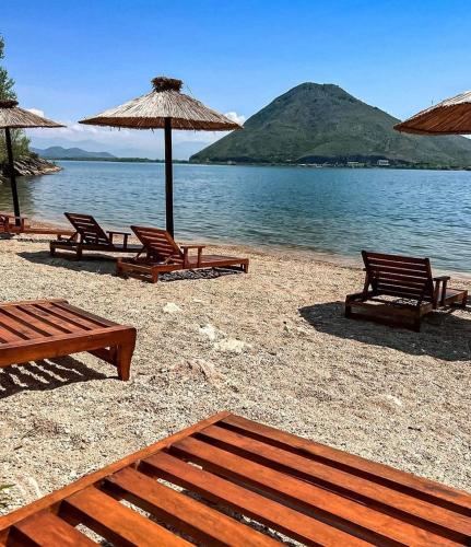 a group of chairs and umbrellas on a beach at Skadar Lake Apartment-Nikola in Podgorica