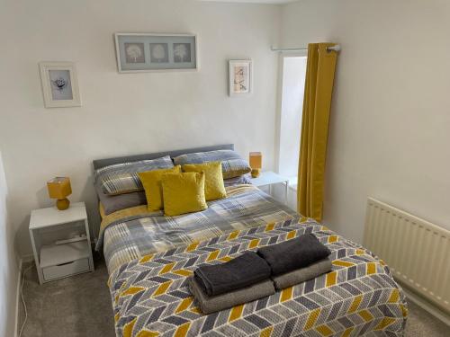 una camera da letto con un letto con cuscini gialli e blu di The Ironstone Miners Cottage a Wilton