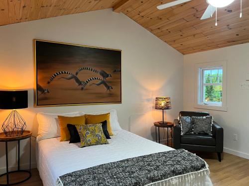 een slaapkamer met een groot bed en een zwarte stoel bij Paradis de Charlevoix - Loft in Baie-Saint-Paul