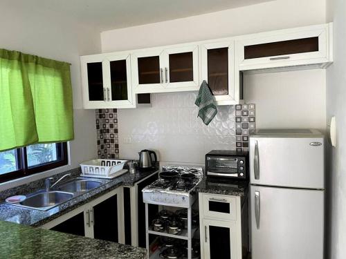 キャバレテにあるCabarette Apartmentsの白いキャビネットと白い冷蔵庫のあるキッチン