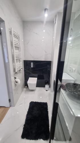 a white bathroom with a toilet and a sink at APARTAMENT De Lux Parkowa Olecko in Olecko