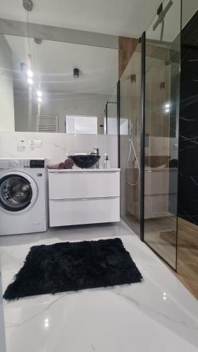 a bathroom with a washing machine and a shower at APARTAMENT De Lux Parkowa Olecko in Olecko