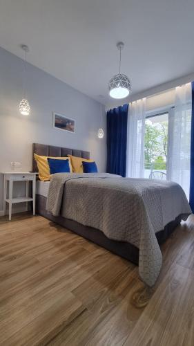 a bedroom with a large bed with blue and yellow pillows at APARTAMENT De Lux Parkowa Olecko in Olecko