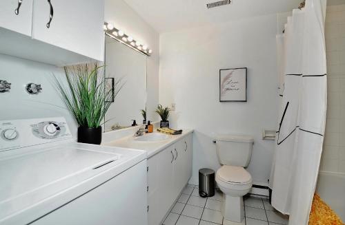 a white bathroom with a toilet and a sink at 51 Chemin de la Corniche in Stoneham