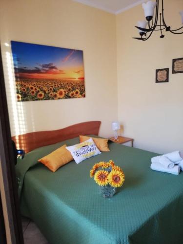 a bedroom with a green bed with a vase of flowers at By the Sea in Terrasini