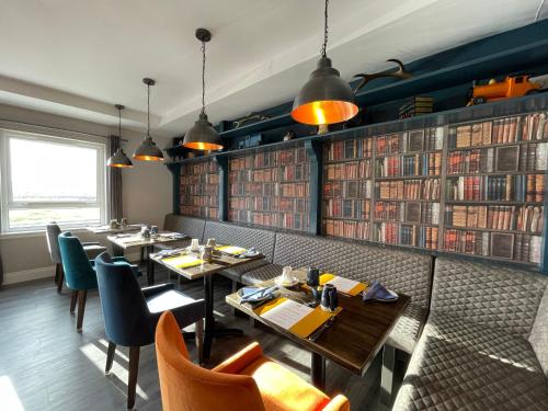 un restaurante con mesas, sillas y libros en Grianaig Guest House & Restaurant, South Uist, Outer Hebrides, en Daliburgh