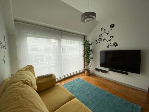 uma sala de estar com um sofá e uma televisão de ecrã plano em Penthouse with terrace and views near Oza's beach em La Coruña
