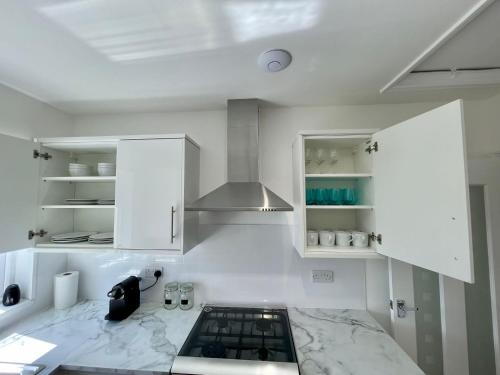 a kitchen with white cabinets and a marble counter top at Cheerful 2-bedroom bungalow with free parking in Newton Poppleford
