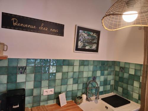 a bathroom with a sink and a sign on the wall at L'Empire D'Essences Appartement in Valréas