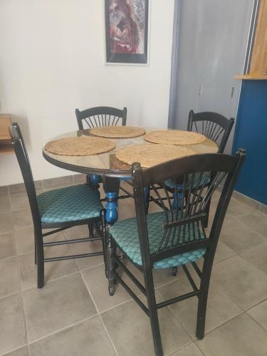 a dining room table with four chairs around it at L'Empire D'Essences Appartement in Valréas