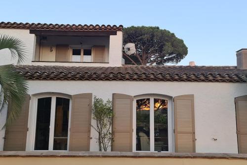 a white house with a window and a palm tree at Ste Maxime Villa 5 etoiles Piscine chauffée et jacuzzi in Sainte-Maxime