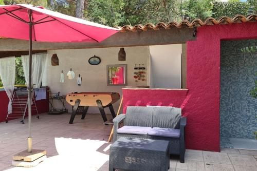 une terrasse avec un mur rouge, une table et un parasol dans l'établissement Ste Maxime Villa 5 etoiles Piscine chauffée et jacuzzi, à Sainte-Maxime