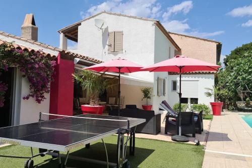 a ping pong table in front of a house with umbrellas at Ste Maxime Villa 5 etoiles Piscine chauffée et jacuzzi in Sainte-Maxime