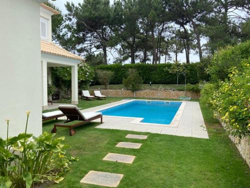 a backyard with a swimming pool and a lawn with a bench at Soltroia Glamorous Villa in Troia