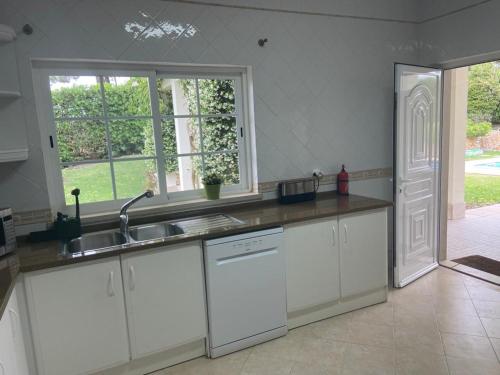 a kitchen with white cabinets and a sink and a window at Soltroia Glamorous Villa in Troia