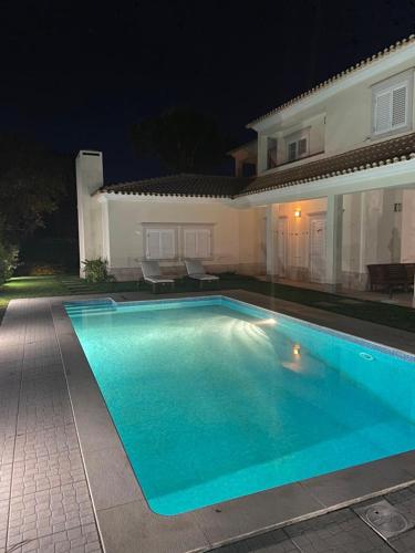 a swimming pool in front of a house at night at Soltroia Glamorous Villa in Troia