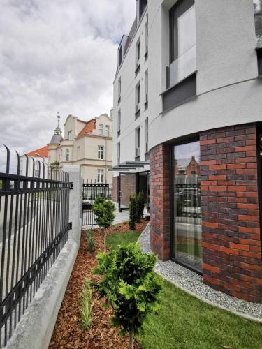 a building with a fence next to a yard at Glow Apartments, Aparthotel Kołłątaja - Wrzeszcz in Gdańsk
