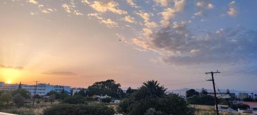 a sunset over a city with a sky with clouds at Eugenia Studios & Apartments in Ialyssos
